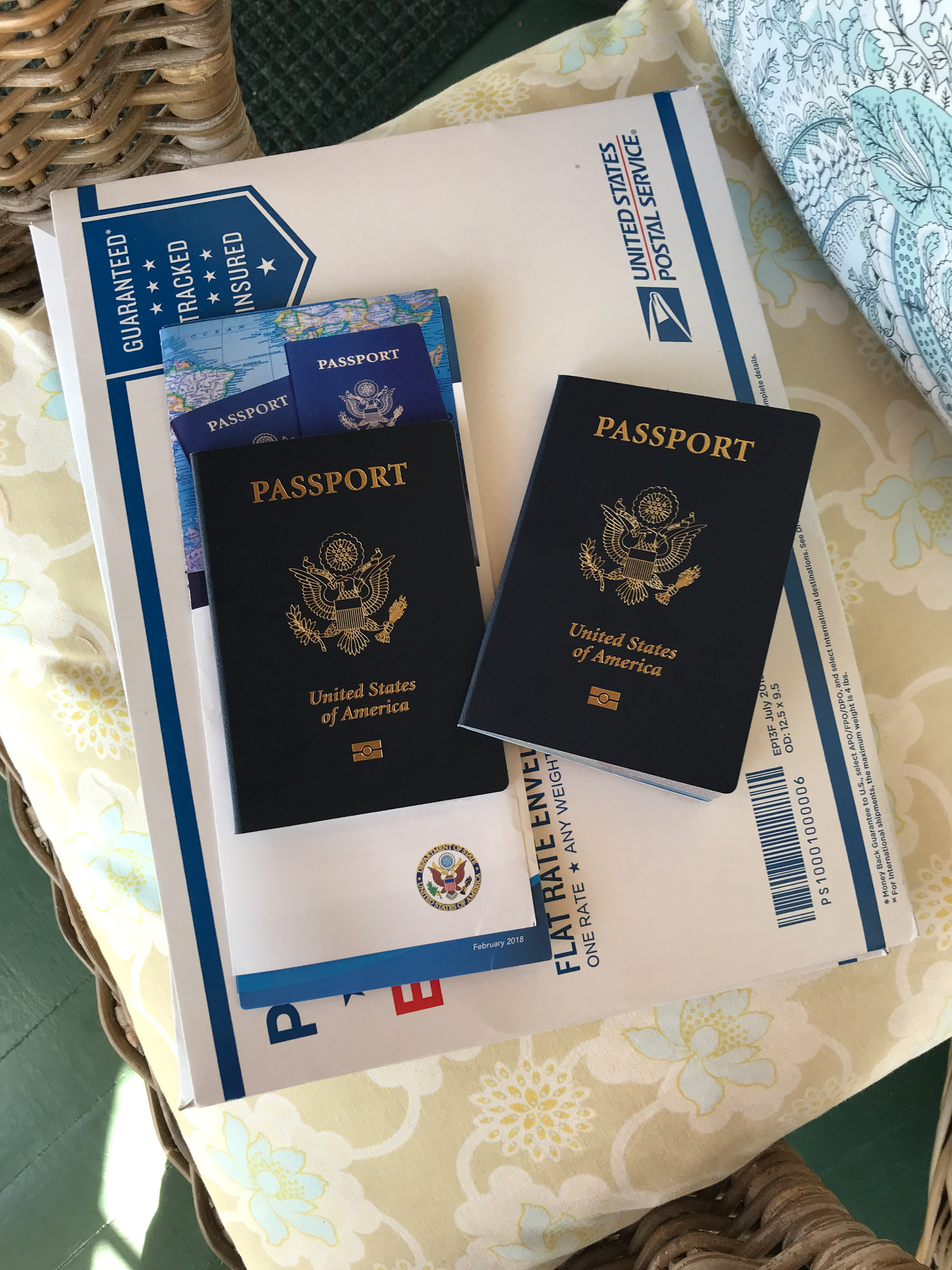 photo of two united states passports on top of usps mailing envelope sitting on porch chair