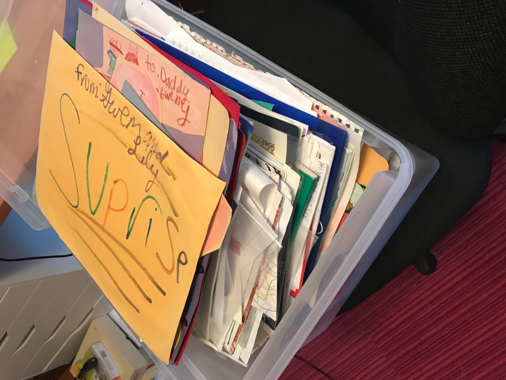 Plastic bin full of of children's artwork and school papers